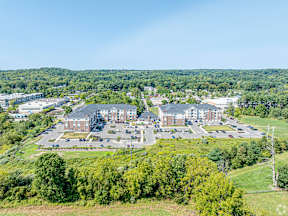 A large building complex surrounded by trees and a parking lot.