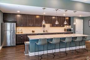A kitchen with a bar and chairs.