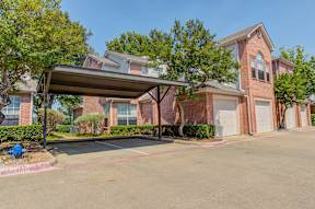 A large brick house with a covered parking area in front.