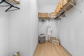 a room with white walls and wooden floors and a closet with wooden shelves