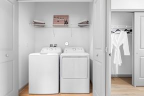 a laundry room with two washer and dryers and a closet