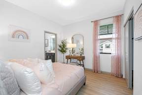 a bedroom with a bed and a window with pink curtains