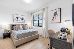 a bedroom with a bed and a desk and a window