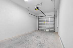 the interior of a garage with white walls and a silver garage door