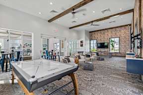 a game room with a pool table and a living room with chairs and a television