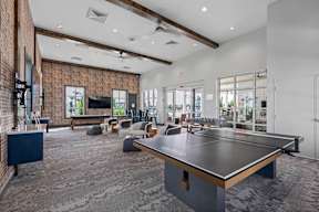 a community room with a ping pong table and lounge chairs