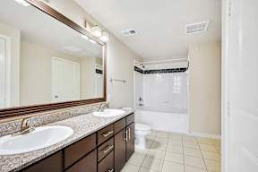 a bathroom with two sinks and a shower and a toilet