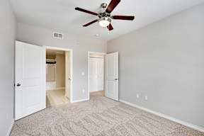 an empty living room with a ceiling fan and a door to a closet