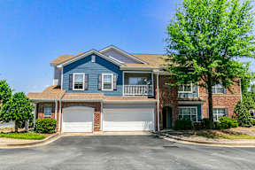 A two-story house with a garage and a tree in front.