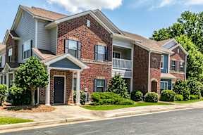 A row of houses with a brick facade and a green lawn in front.