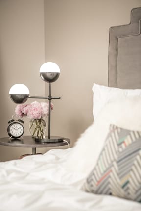 a bed with white sheets and a nightstand with a clock and a vase at the Vintage on Selby in St. Paul, MN