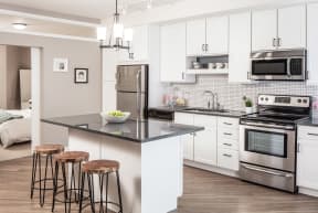 a kitchen with stainless steel appliances and a counter with three stool at the Vintage on Selby in St. Paul, MNs