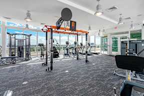 A gym with a variety of equipment including a squat rack, bench press, and a rowing machine.