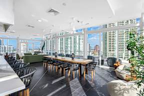 A large conference room with a long table and chairs, a green sofa, and a view of the city through the windows.