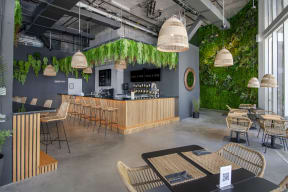 a restaurant with plants on the wall and a bar with tables and chairs