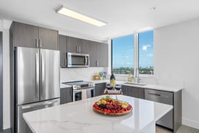 a kitchen with stainless steel appliances and a large island with a fruit centerpiece