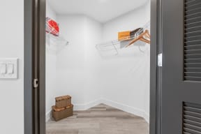 room with white walls and wood floors and a closet with two hanging racks