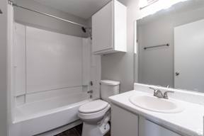A white bathroom with a toilet, sink, and bathtub.