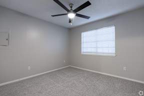 A room with a ceiling fan and a window with blinds.