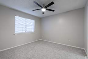 A room with a ceiling fan and a window with blinds.