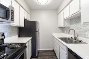 A kitchen with black appliances and white cabinets.