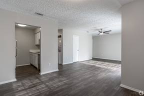 A room with a ceiling fan and a kitchenette.