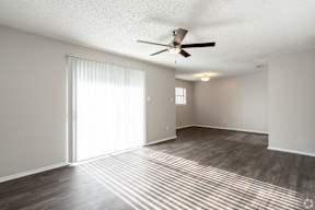 A room with a ceiling fan and sliding glass doors.
