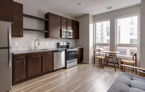 a kitchen with dark wood cabinets and stainless steel appliances  at RoCo Apartments, Fargo, North Dakota