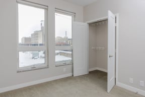 a bedroom with three large windows and a closet  at RoCo Apartments, Fargo, North Dakota