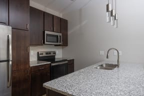 a kitchen with granite countertops and dark wood cabinets  at RoCo Apartments, Fargo, North Dakota
