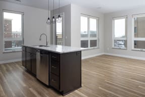 an open kitchen with a large island with a sink and a dishwasher  at RoCo Apartments, Fargo, North Dakota