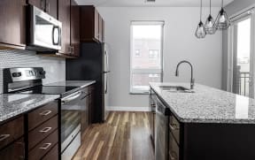 a kitchen with granite countertops and dark wood cabinets  at RoCo Apartments, North Dakota, 58102