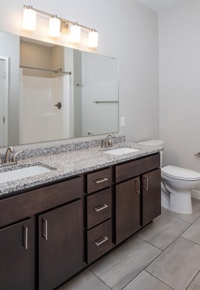 a bathroom with a toilet sink and mirror  at RoCo Apartments, Fargo, ND, 58102