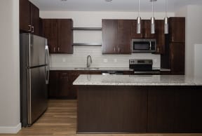 a kitchen with dark wood cabinets and a white counter top  at RoCo Apartments, Fargo, 58102