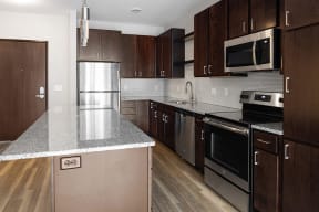 a kitchen with dark wood cabinets and stainless steel appliances  at RoCo Apartments, Fargo, North Dakota