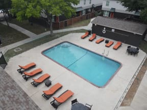 an aerial view of a swimming pool with orange lounge chairs