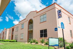 Exterior view of Los Cedros Apartments building with landscaping