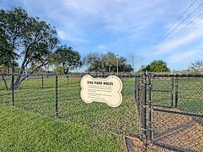 Gated dog park with entry sign at Los Cedros Apartments