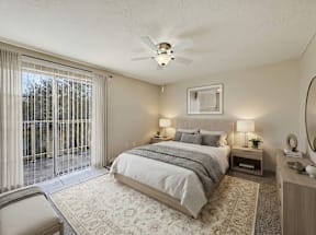 A bedroom with a large bed, a chair, and a ceiling fan.