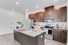 A kitchen with brown cabinets and a granite countertop.