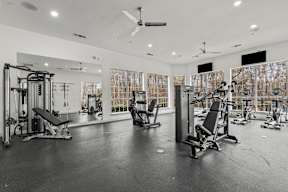 A spacious gym with various exercise equipment and a mirrored wall.