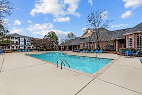 A large swimming pool surrounded by blue lounge chairs.