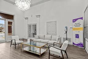 A living room with a glass coffee table and white furniture.