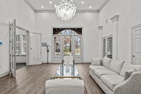 A modern living room with a glass coffee table and a grey sofa.
