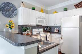 A kitchen with white cabinets and a marble countertop.