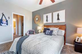 A bedroom with a bed, a ceiling fan, and a wall hanging.
