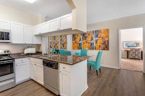A kitchen with white cabinets and a wooden floor.