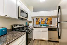 A kitchen with white cabinets and a granite countertop.