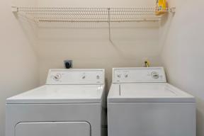 Two white front loading washing machines in a laundry room.