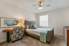 A bedroom with a bed, chair, and painting.